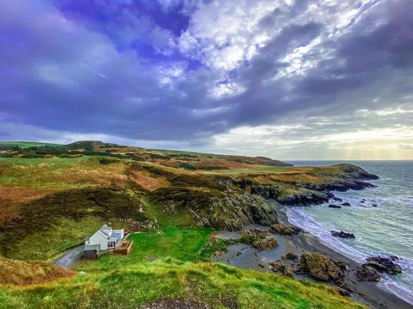 a house on a cliff next to the ocean at Portamaggie Cottage in Portpatrick