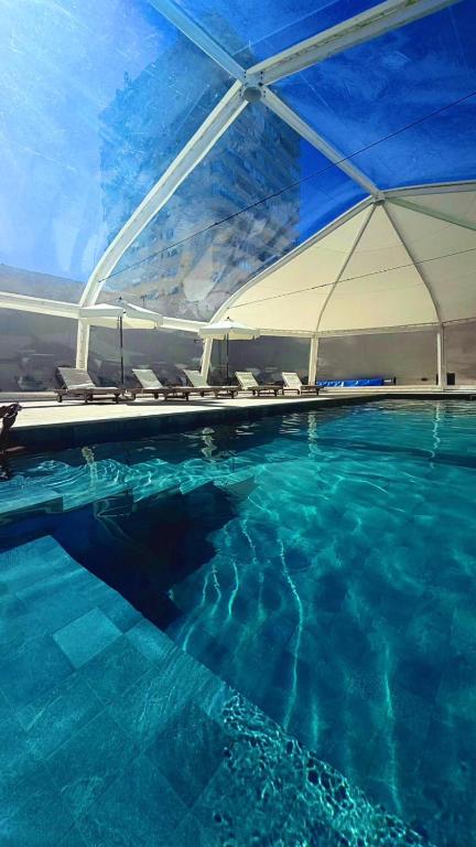 a large swimming pool with chairs and an umbrella at Hotel Florinda in Punta del Este