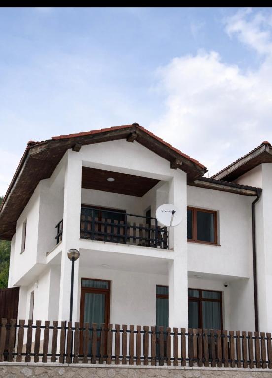 a white house with a fence in front of it at Четири сезона 12 in Stoykite
