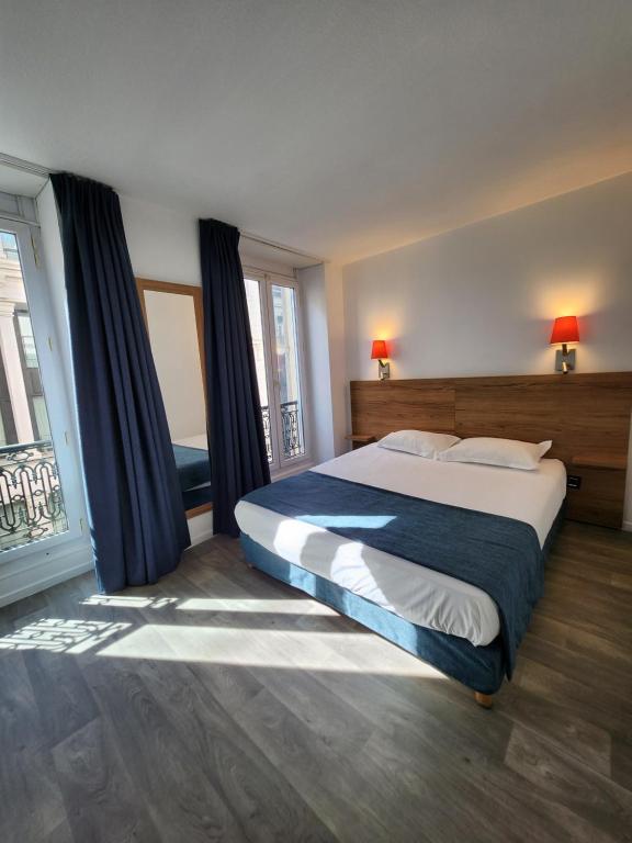 a bedroom with a large bed and a window at Hôtel Alizé in Cannes
