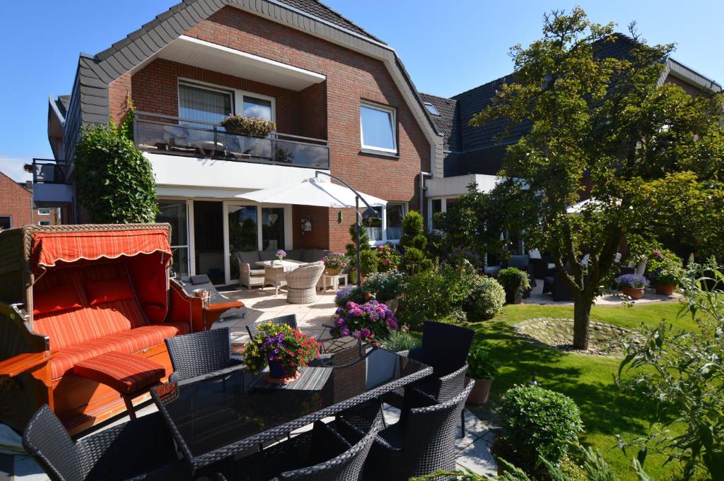 een huis met een patio met een oranje bank en stoelen bij Haus Mühlentrift Döse in Cuxhaven