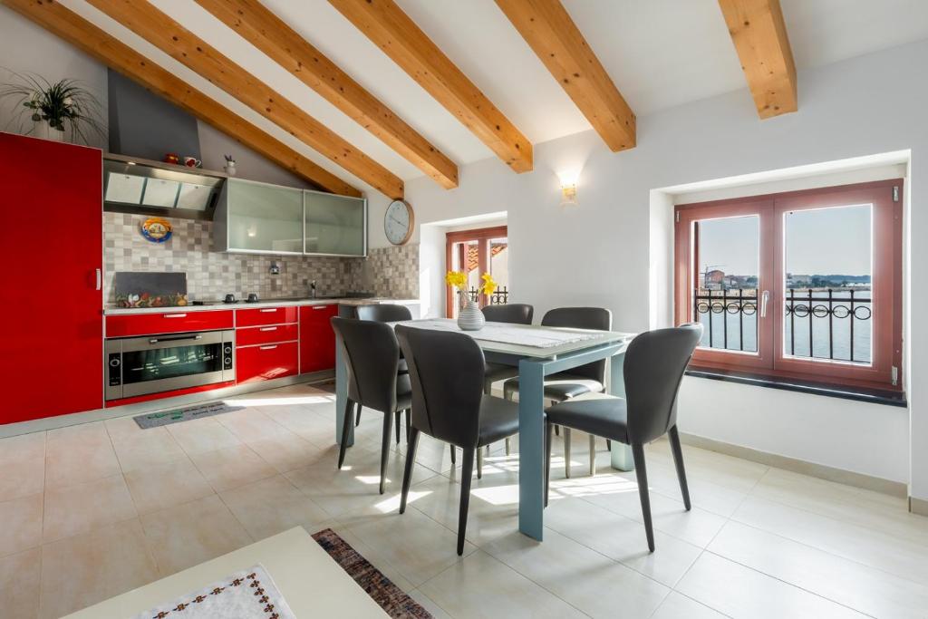 a kitchen with red cabinets and a table and chairs at Apartment Seafront Mia in Umag