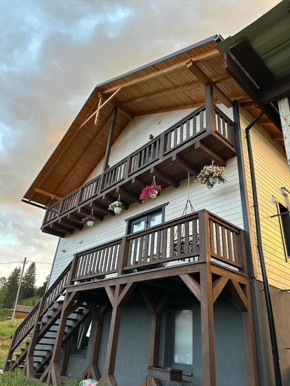 a balcony on the side of a house with flowers at Котедж HOLIDAY HOUSE in Yablunytsya