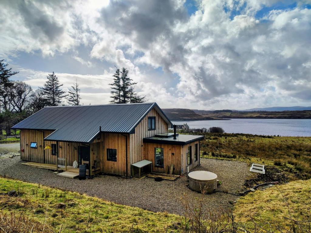 a large wooden cabin with a lake in the background at Faodail House in Portree