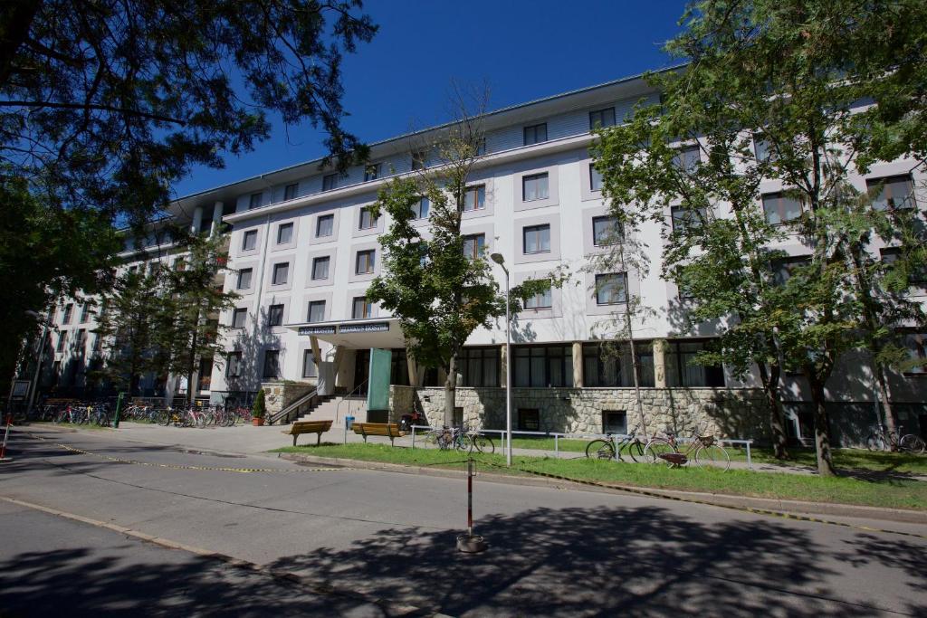 un edificio blanco con un árbol delante en Study K & M Hotel en Debrecen