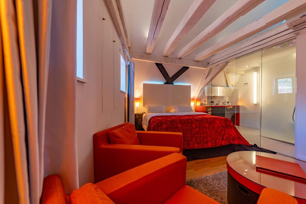 a bedroom with a bed and a red chair at Le B. Suites, Chambres & Restaurant in Riquewihr