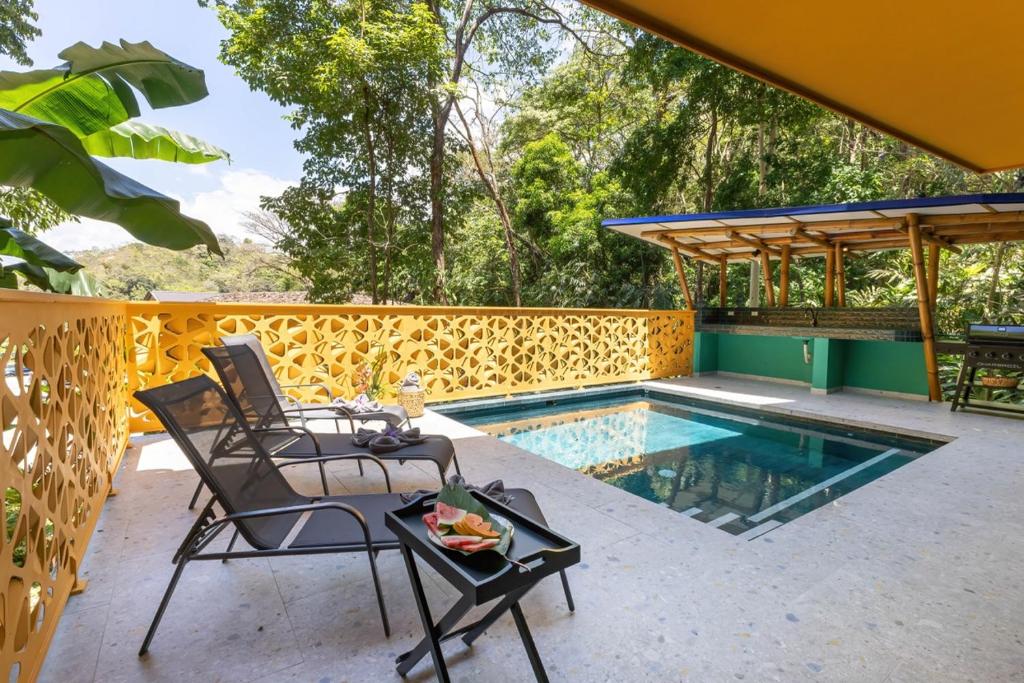 a patio with a table and chairs next to a swimming pool at Dos Olas Ocean-Inspired Luxury Villa in Quepos