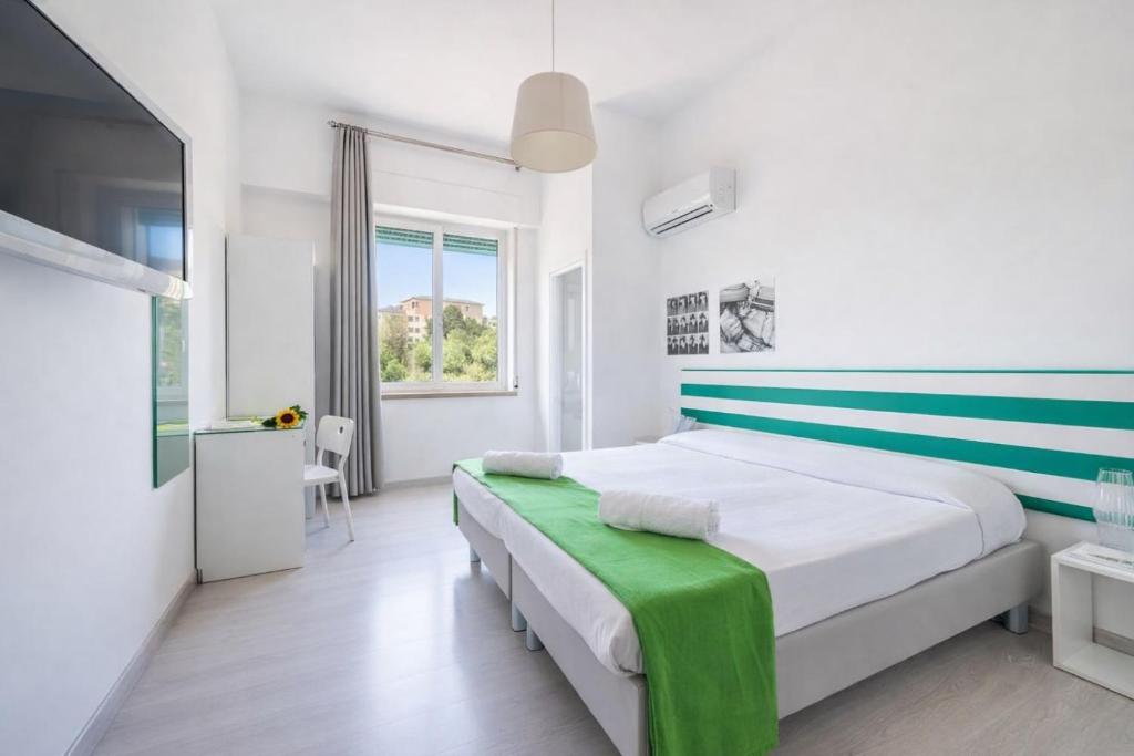 a white bedroom with a green and white striped headboard at Hotiday Sorrento Capo in Sorrento