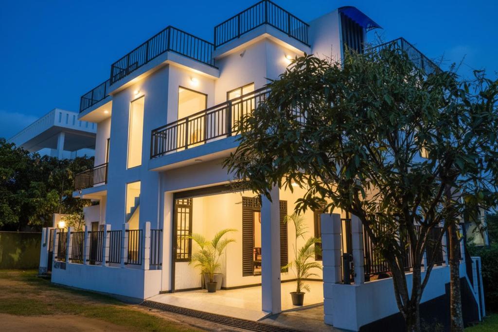 a white house with a tree in front of it at Sea Line Villa in Galle