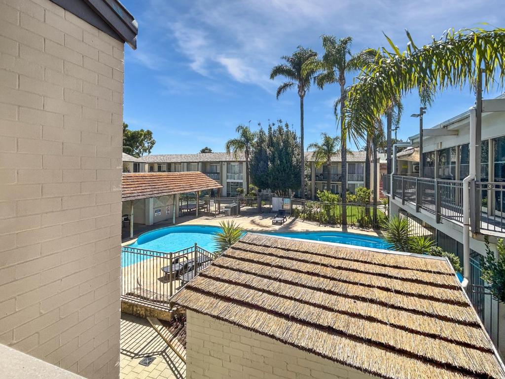a view of the swimming pool at a resort with palm trees at Charming Studio Apartment in Mandurah in Mandurah
