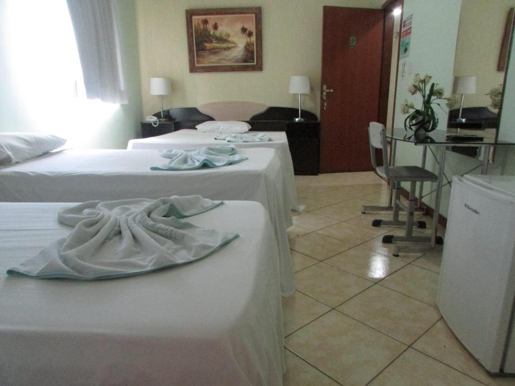 a hotel room with two beds and a table at Hotel Industrial Contagem in Contagem