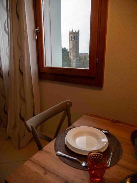 a table with a plate and a window with a castle at Dimora Porta Vicenza-Montagnana in Montagnana