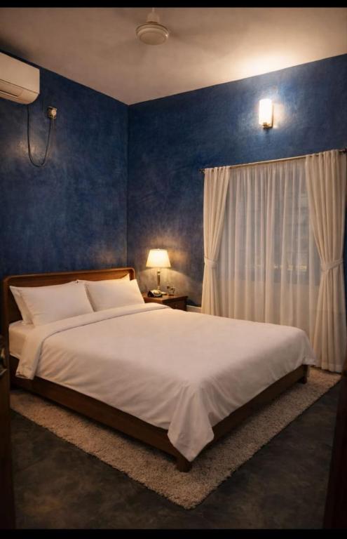 a bedroom with a large bed with a blue wall at Gravity Groups Blue Lagoon Villa in Kuilapayam