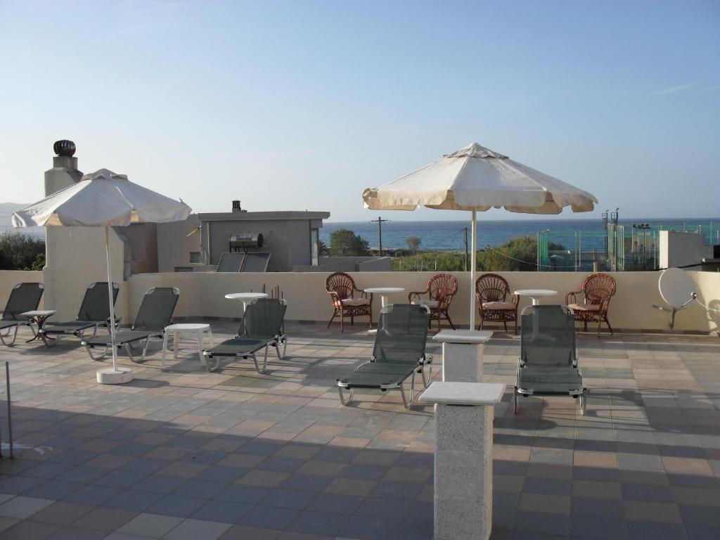 a patio with chairs and tables and umbrellas at La Santre Villa in Amoudara Herakliou