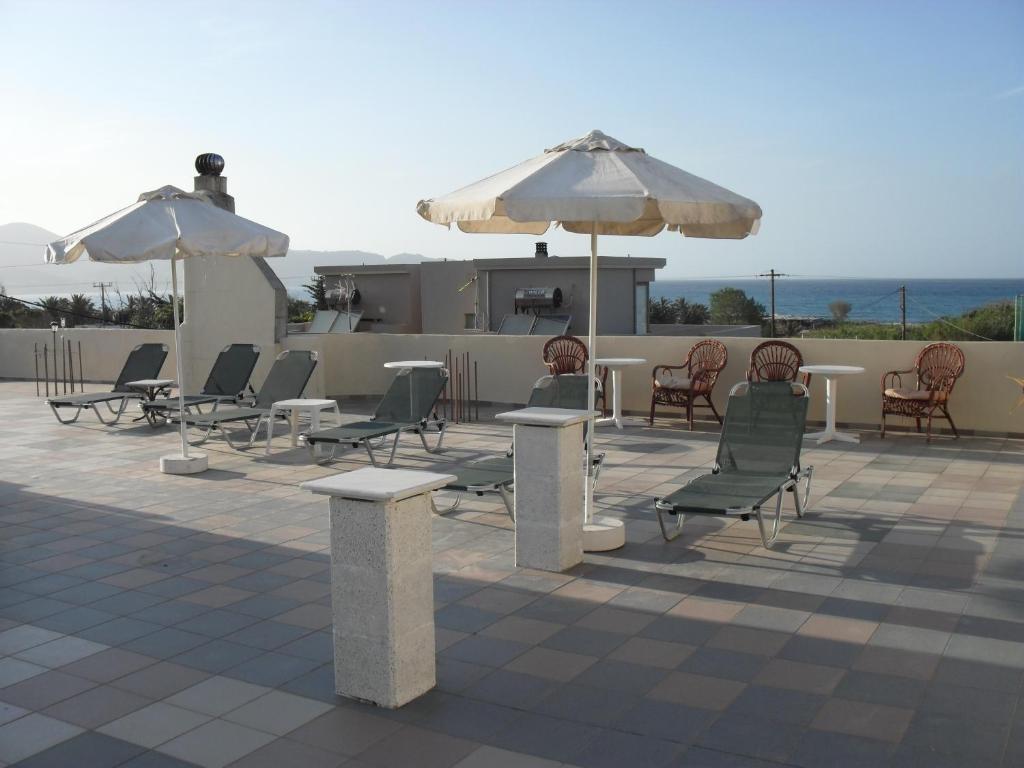 a group of chairs and tables and umbrellas on a patio at La Santre Villa in Amoudara Herakliou