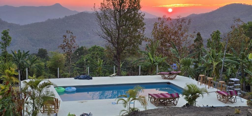 a pool with chairs and a sunset in the mountains at Mountain springs resort in Ban Nong Khieo