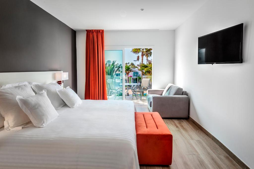 a bedroom with a large white bed and a television at Barceló Corralejo Sands in Corralejo