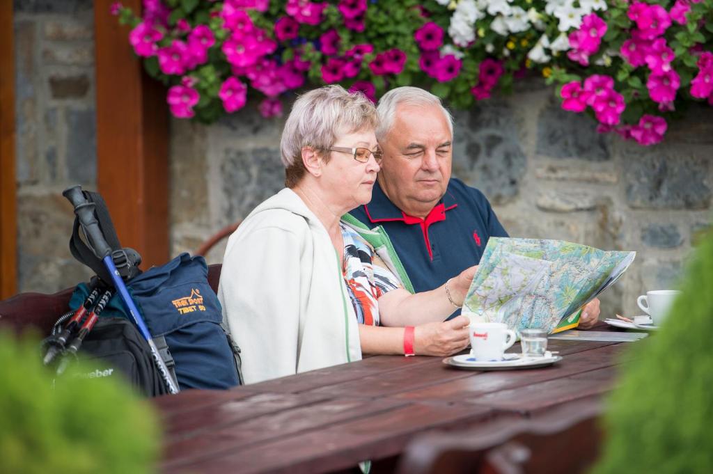 Un uomo e una donna seduti a un tavolo con una mappa di Privat u Babky a Ždiar
