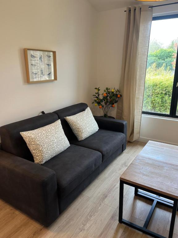 a black couch in a living room with a window at La Renardière in Foreste