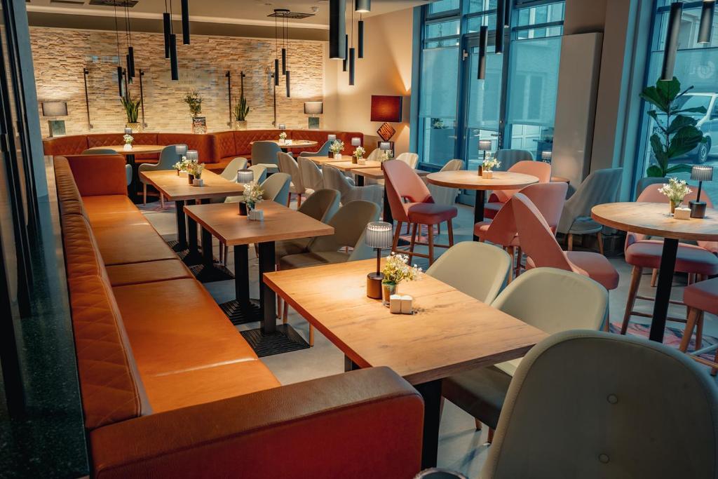 a restaurant with wooden tables and chairs and windows at City Park Hotel in Frankfurt Oder