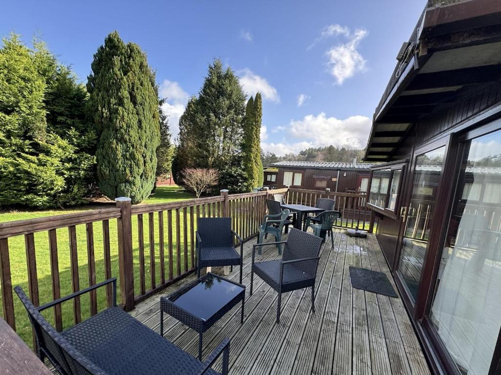 a patio with chairs and tables on a wooden deck at Lodge 18 - Caer Beris Park - No Tradesmen in Builth Wells