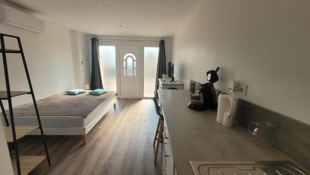 a bedroom with a bed and a kitchen with a counter at Studio NEUF et élégant avec CLIM in Tarbes