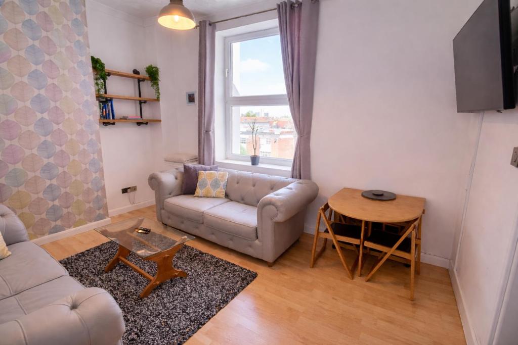 a living room with a couch and a table at Southsea Escape - 2 double bedrooms apartment - PARKING PERMITS INCLUDED in Portsmouth