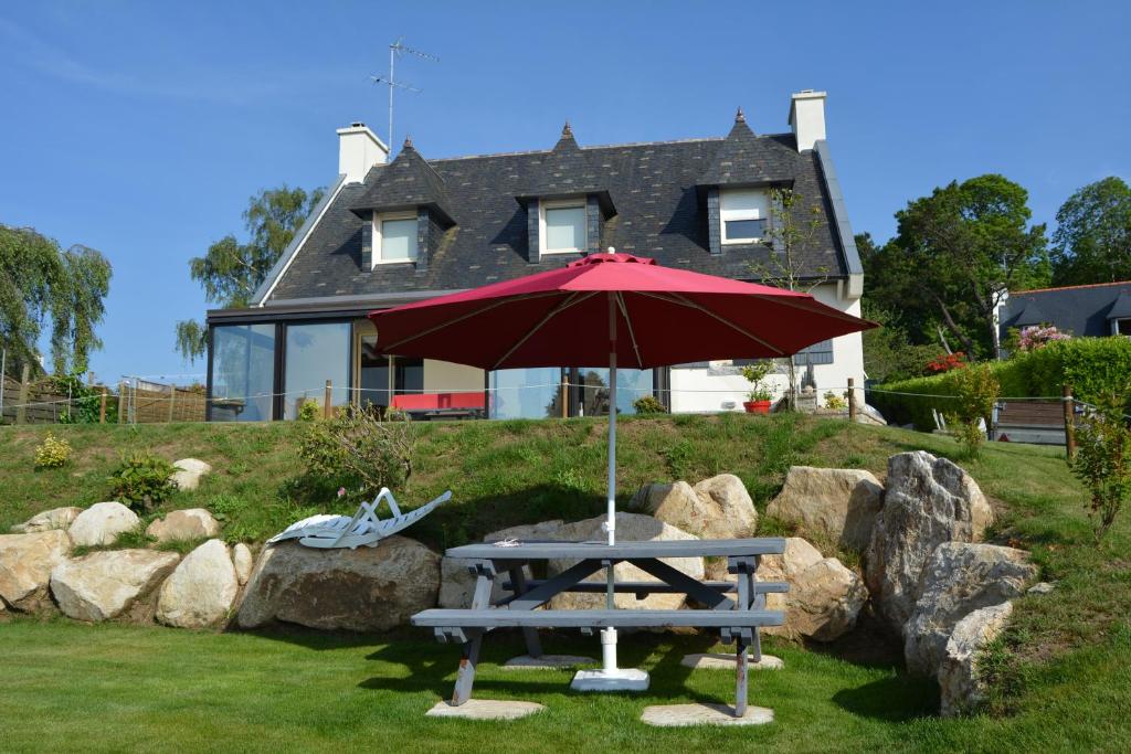 a picnic table with an umbrella in front of a house at La Belle Etoile in Plomelin