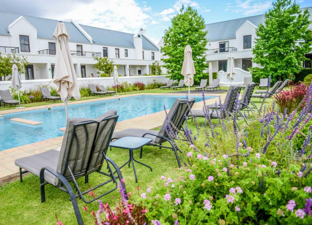 a row of chairs with umbrellas next to a pool at Collection Luxury Apartments 31 Winelands Lodge in Stellenbosch