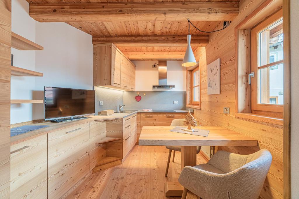 a kitchen with wooden cabinets and a wooden table and chairs at The Love Chalet in Falcade