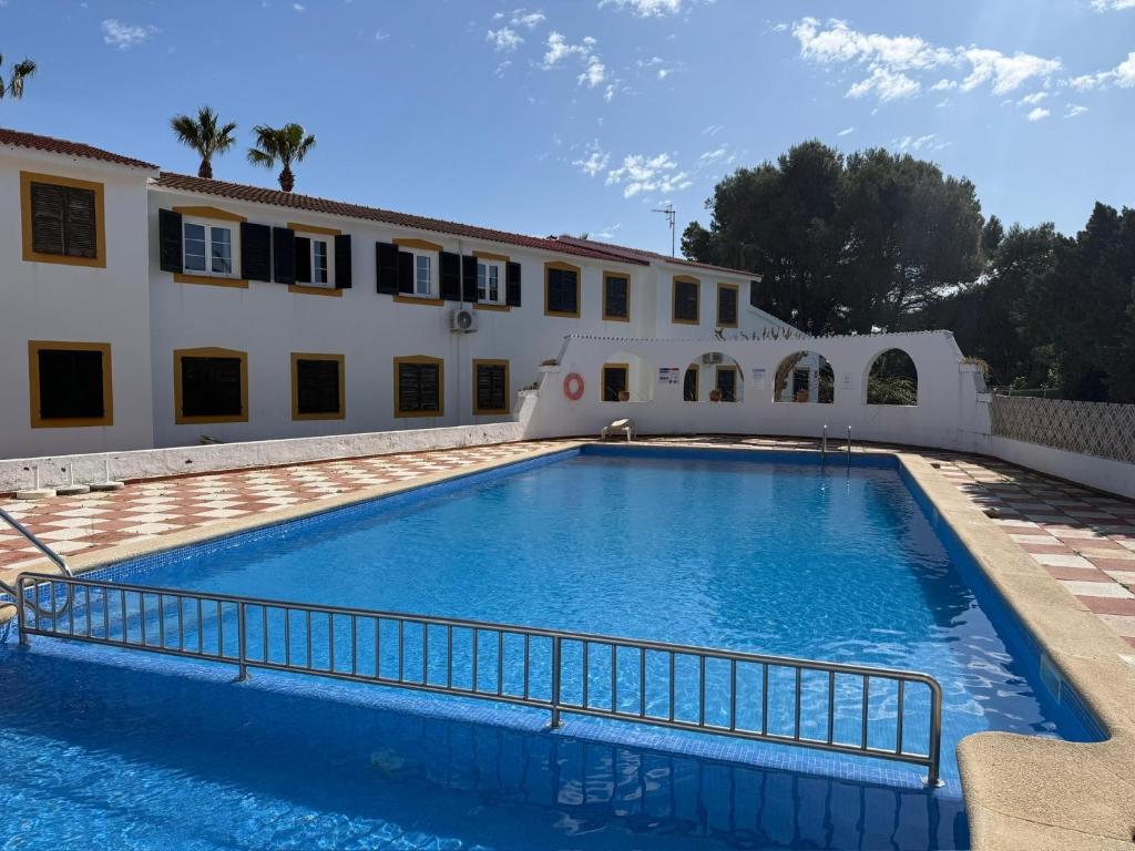 a large swimming pool in front of a building at Apartamento Cala En Bosch B10 in Cala en Bosc