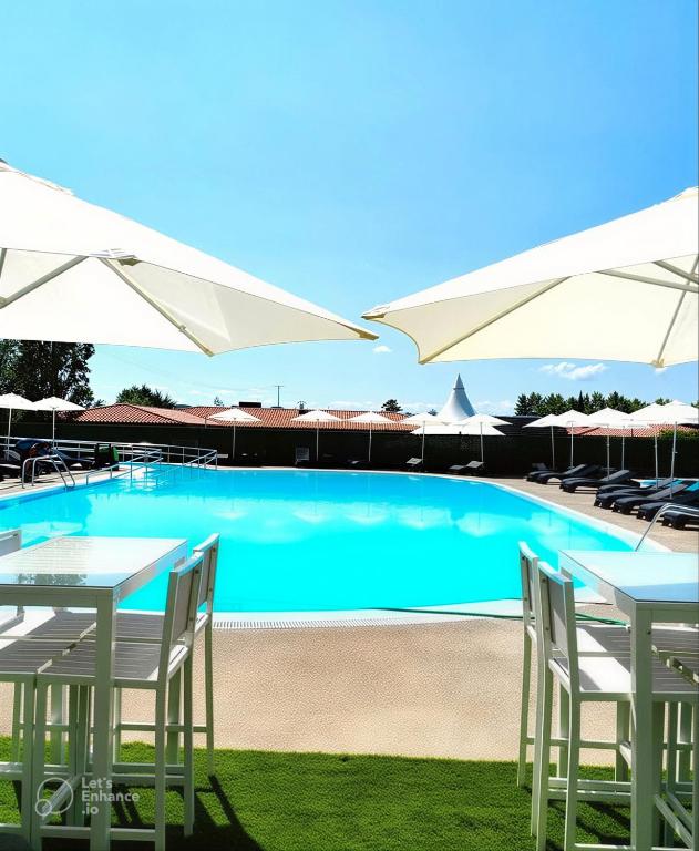 a swimming pool with two tables and white umbrellas at Natura Resorts in Casalarreina