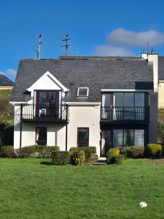 a white house with a balcony and a yard at Harbour View Lodge in Dromod