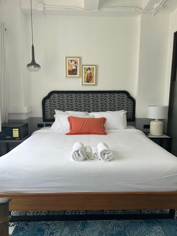 a bedroom with a large white bed with towels on it at Chinoir Boutique Phuket Town in Phuket