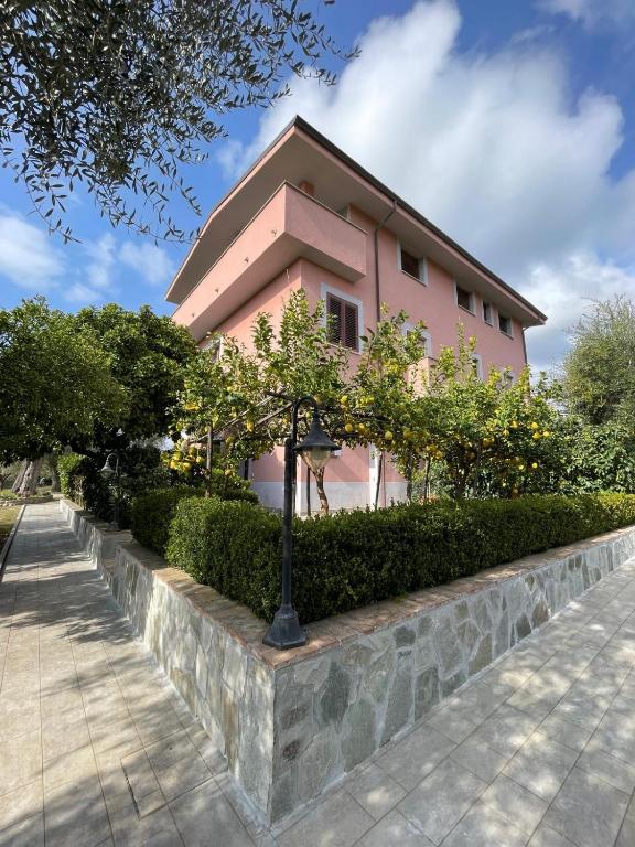 a pink building with trees in front of a sidewalk at Villa Rosada in Palinuro