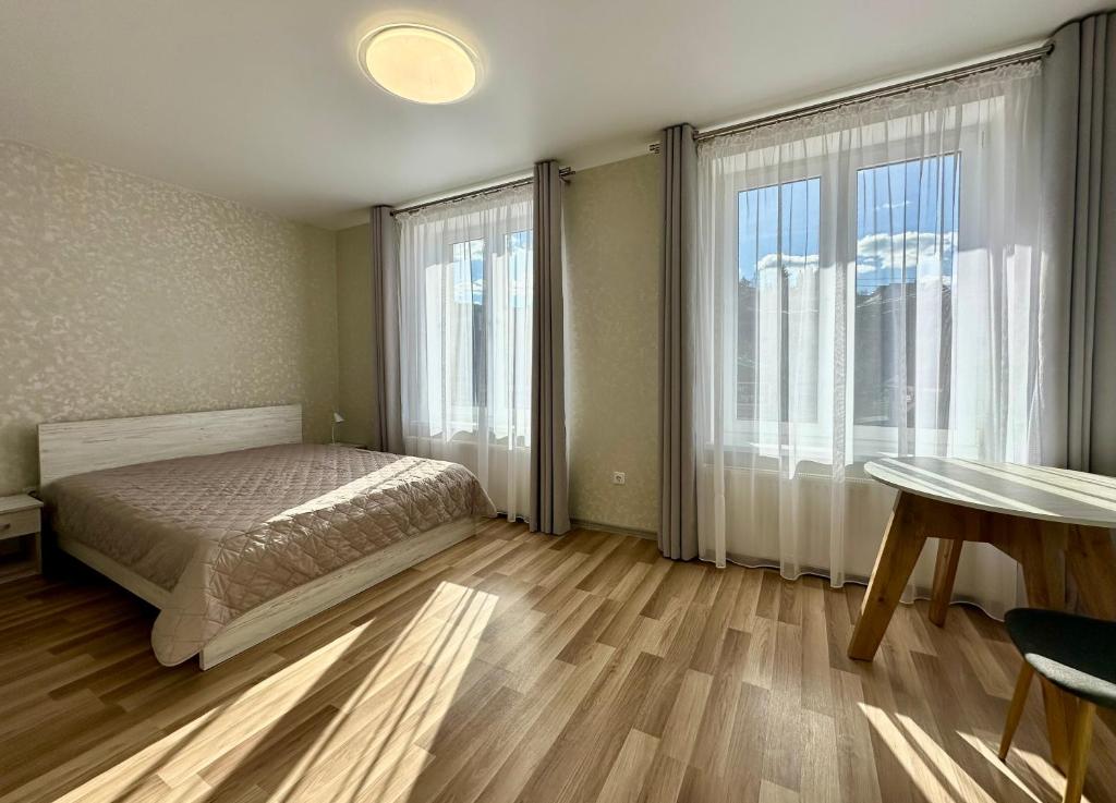 a bedroom with a bed and a table and windows at Апартаменти Пасаж 2 in Skhidnitsa