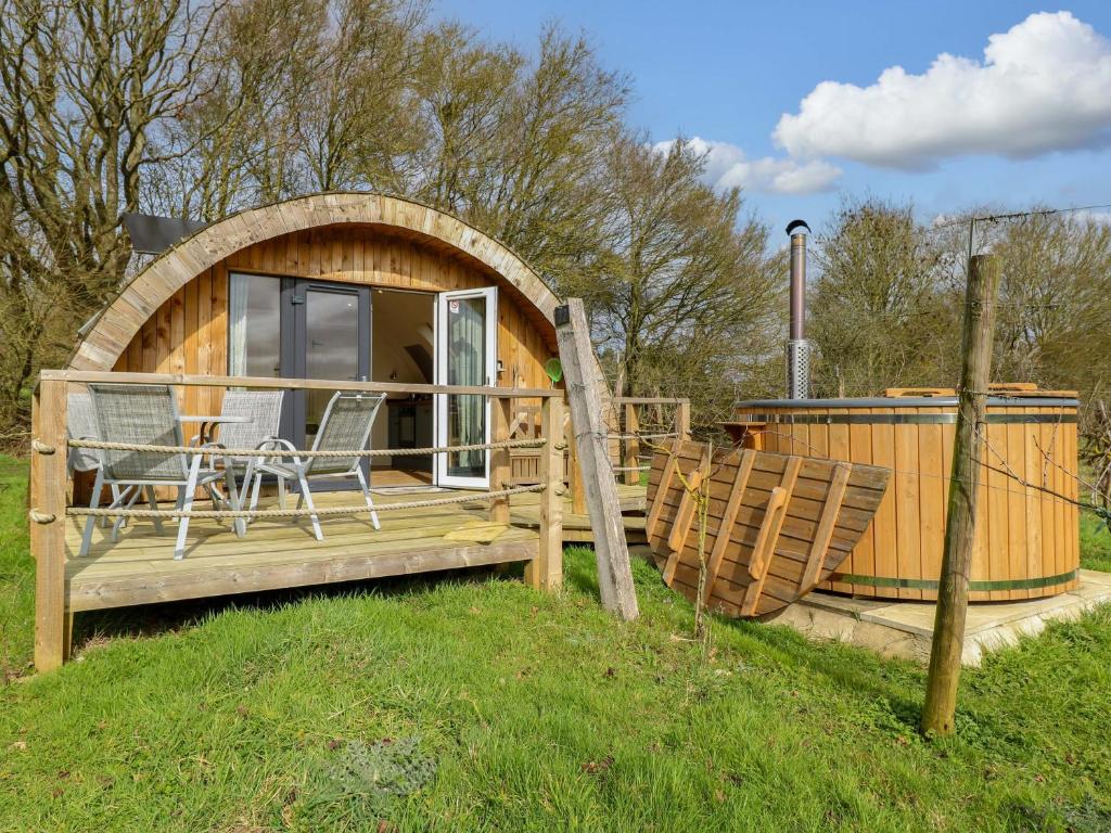 a small cabin with a deck with a table and chairs at Vine View in Halesworth
