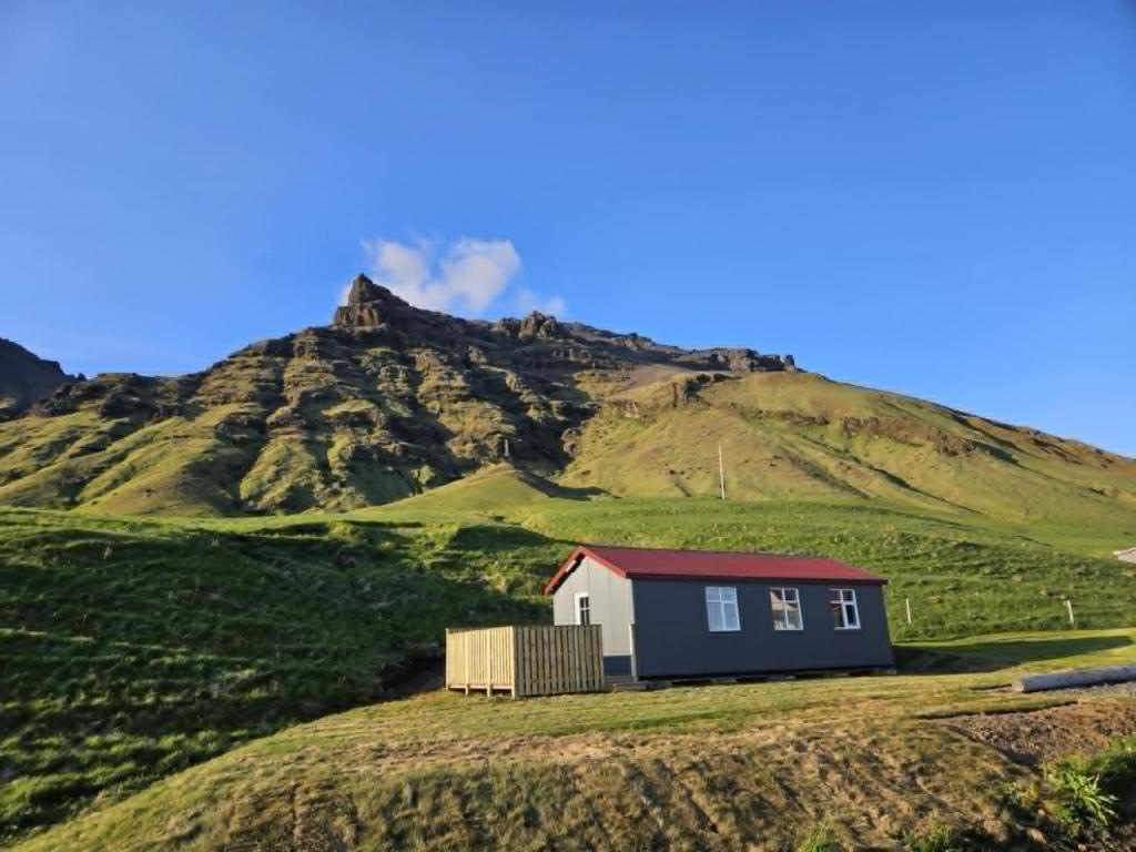 a house on a hill with a mountain in the background at Mountain Cabin at Rauðafell in Hvolsvöllur