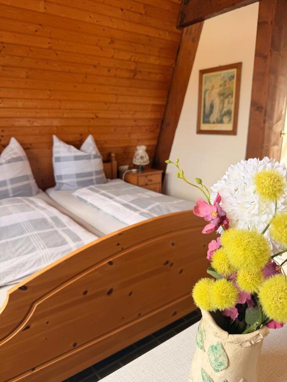 a bedroom with a bed and flowers in a vase at Gästezimmer Ferienhaus Waldblick in Sonnenbühl