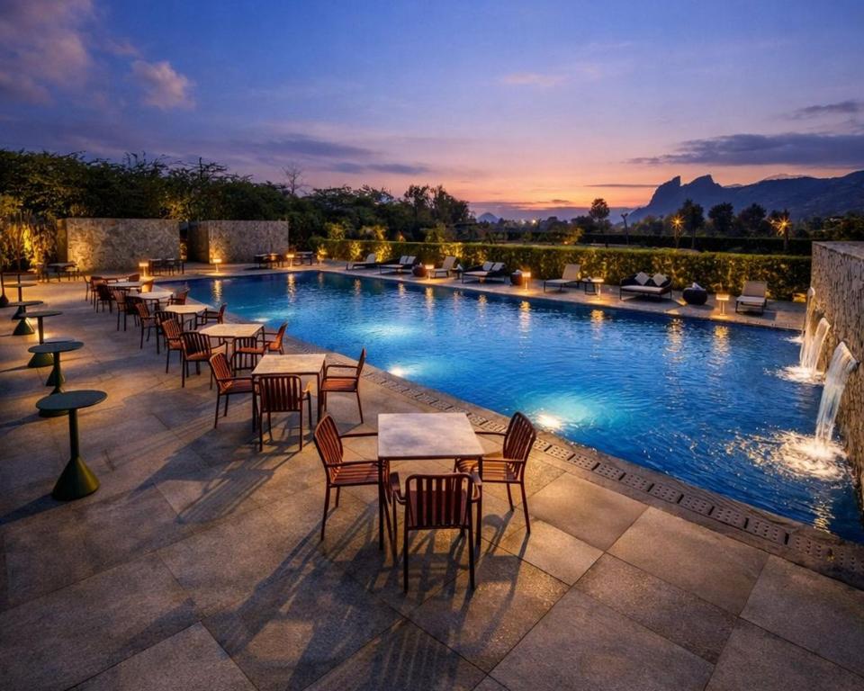 a row of tables and chairs next to a swimming pool at Avisa Hotel & Resort Abu Road - Luxury Pool & Mountain View in Ābu Road