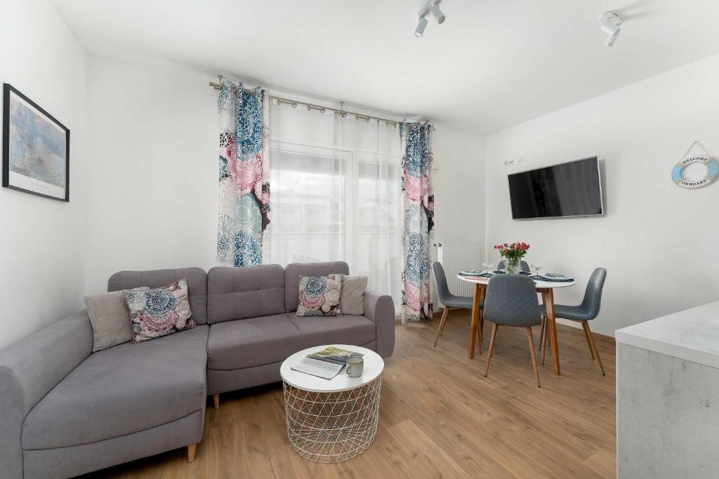a living room with a couch and a table at Sunset Resort Jasny Apartament z 1 Sypialnią 500 m od Plaży, Balkon & Parking by Noclegi Renters in Grzybowo
