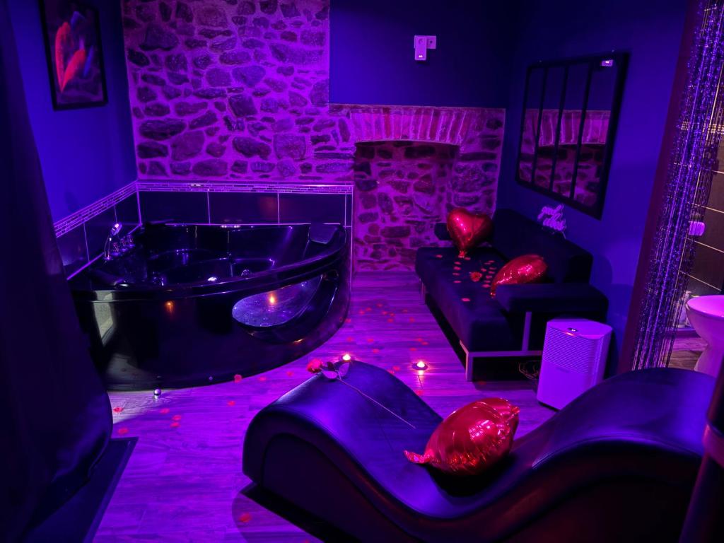 a room with a tub and a couch in a room with purple lights at Spa love room in Donges