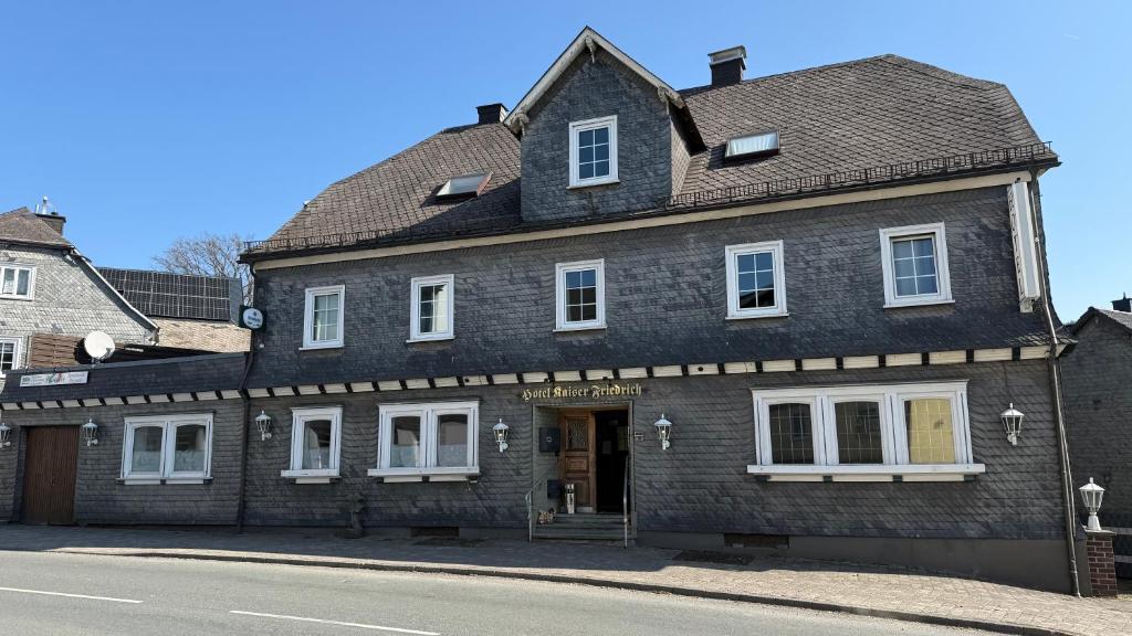 an old brick building with white windows on a street at Hotel Kaiser Friedrich in Bad Berleburg