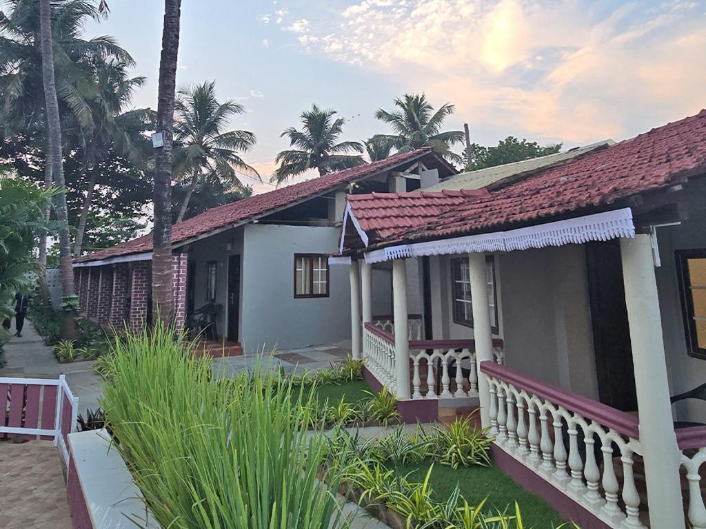 a house with a red roof and some palm trees at M Beach Resort in Colva