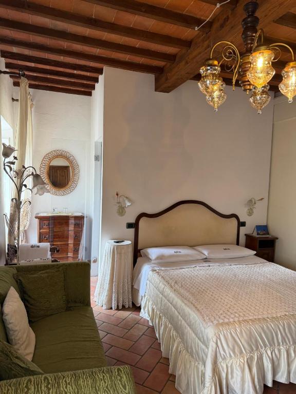 a bedroom with a bed and a couch and a chandelier at Affittacamere Casa Delle Rose in Antria
