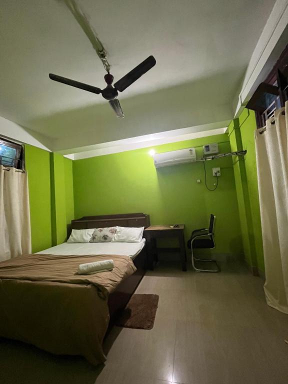 a green room with a bed and a ceiling fan at Anigo Cottage Naharlagun in Bacha