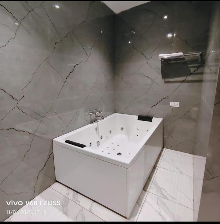 a white tub in a bathroom with marble walls at Hotel Bhumi Residency in Pānīpat