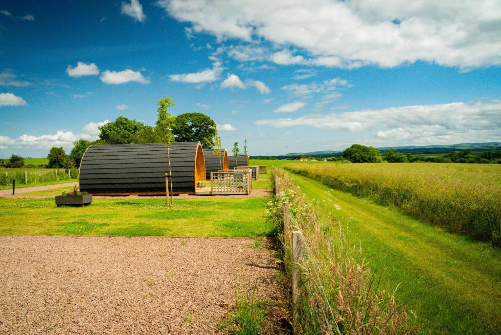 a barn sitting in a field next to a fence at Jerusalem Farm Pods in Tranent