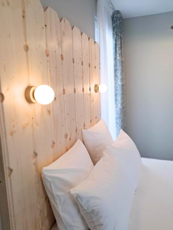 a bed with white pillows and a wooden headboard at Hôtel du Cheval Blanc Brunstatt in Brunstatt