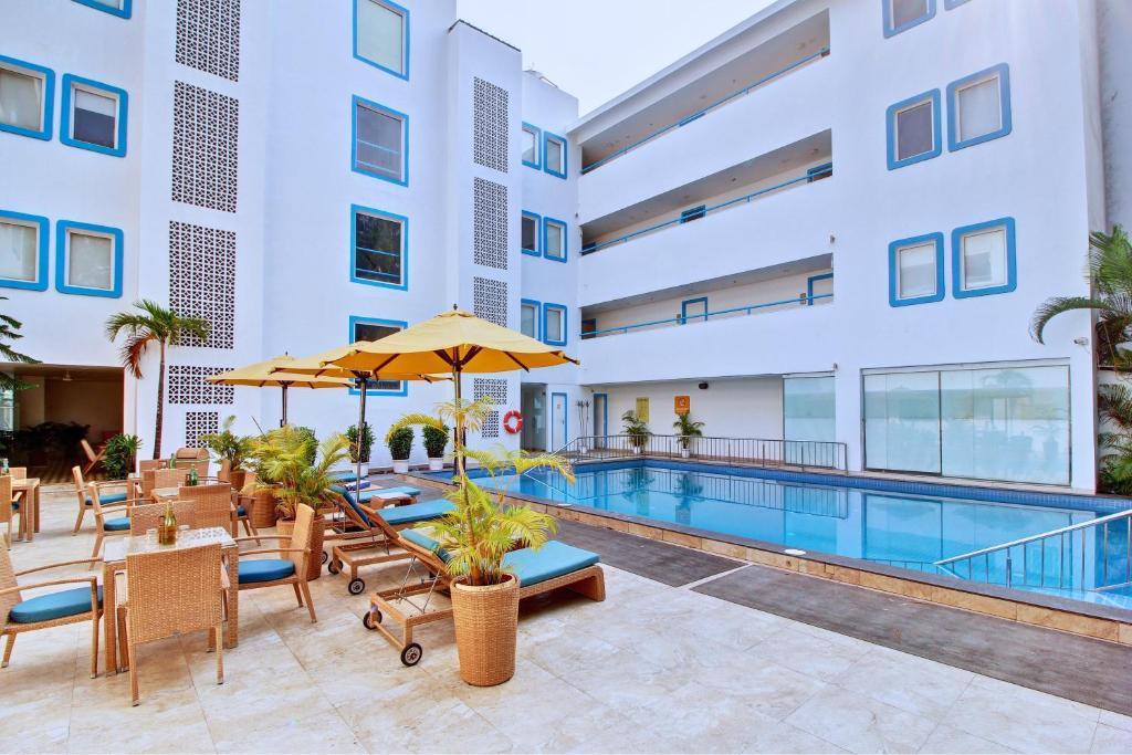 a swimming pool with tables and chairs and a hotel at Hotel Vilmaris Breeze in Calangute